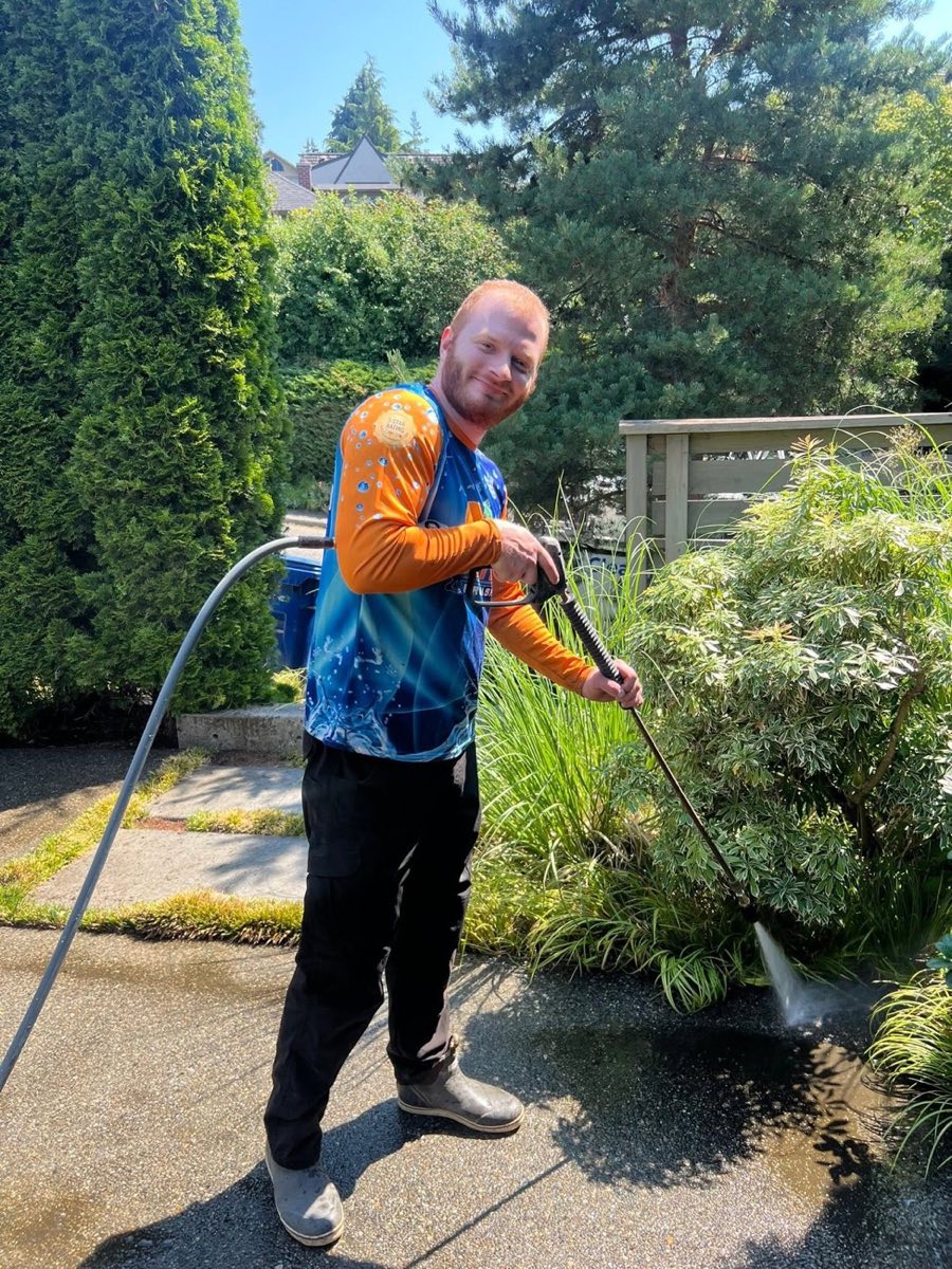 Dylan of Seattle ProWash rinsing landscaping after a cleaning job
